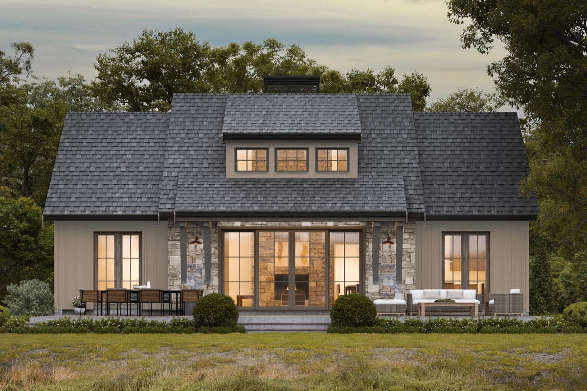 House plan exterior. Two-story home with a gabled roof, stone accents, and a dormer. Features a patio with seating.
