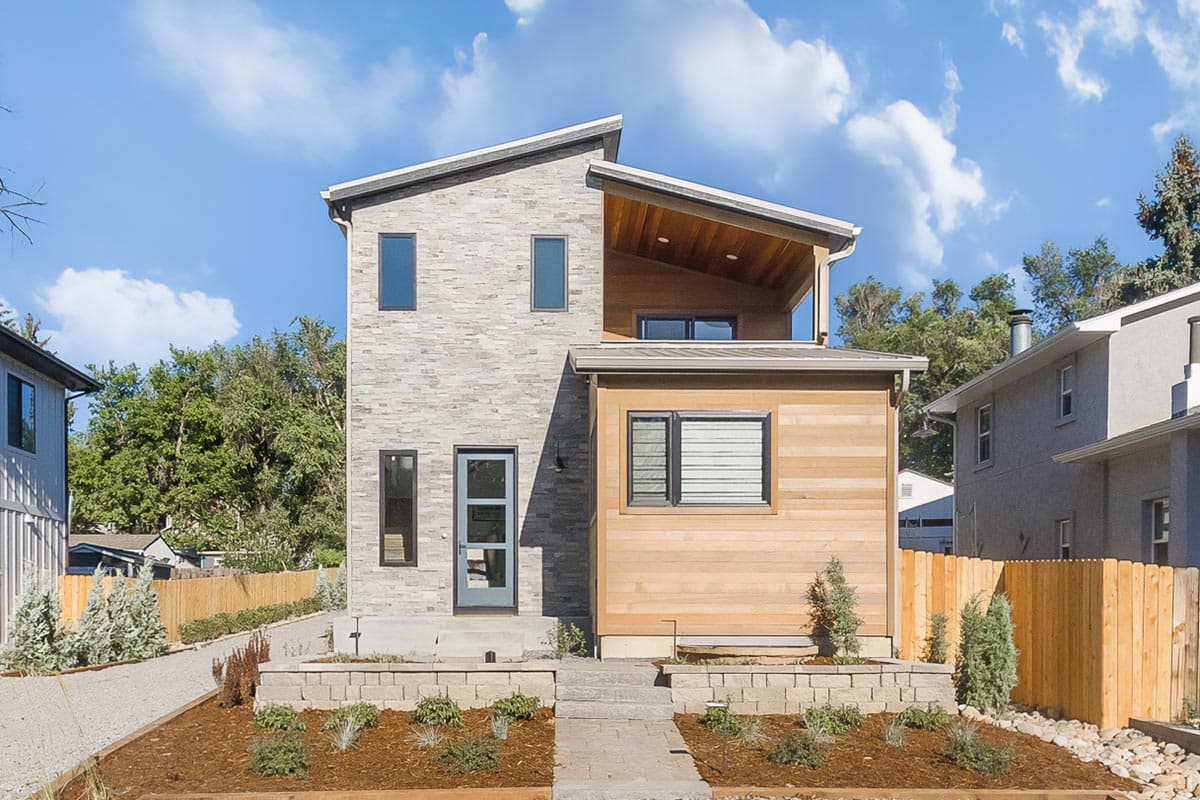 Modern house plan exterior with stone facade, wood siding, and angled rooflines. Two stories with a second-story balcony.