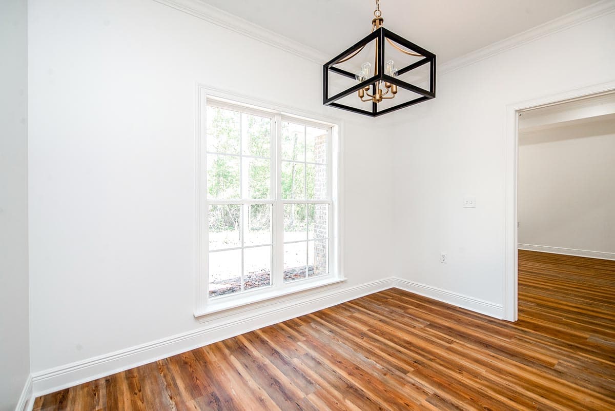 Interior view of room with wood-look flooring, large window, and geometric chandelier. Opens to another room.