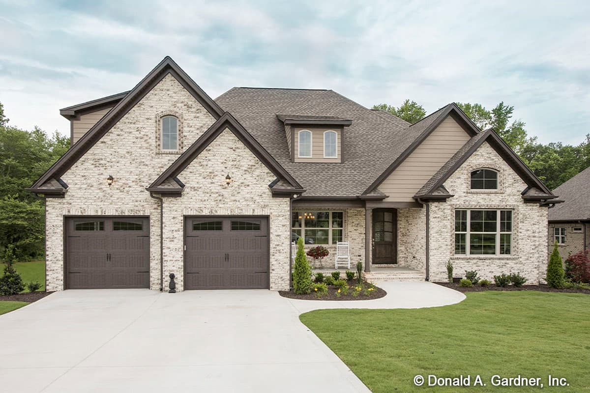 House plan exterior featuring a two-story design with brick facade, multiple gables, arched windows, and a front-entry garage.