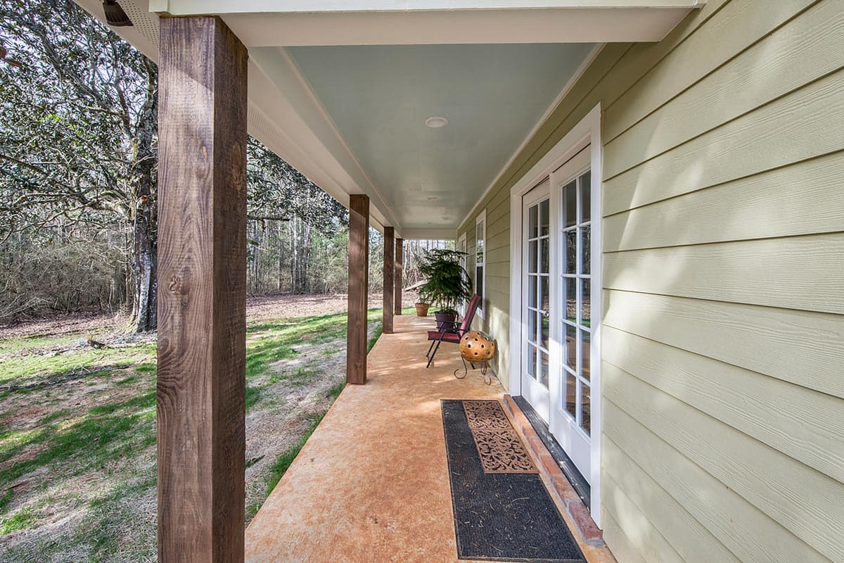 House plan exterior showing a covered porch with wood posts, double doors, and light green siding.