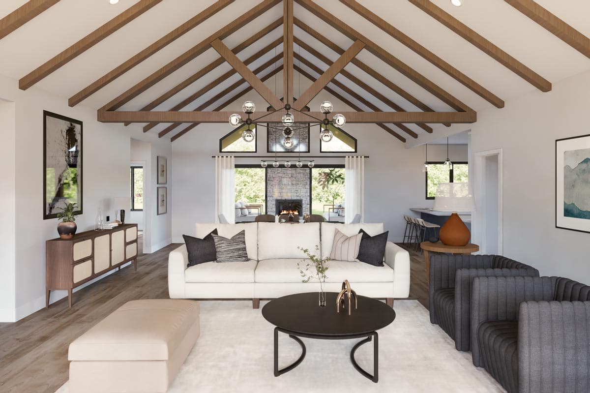 Great room with vaulted beamed ceiling, stone fireplace, large windows, and open kitchen with island.