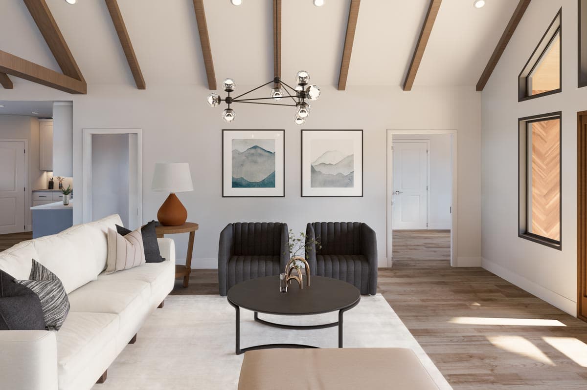 Living room with vaulted ceiling, exposed wooden beams, two framed art pieces, and a large window with wood inlay.