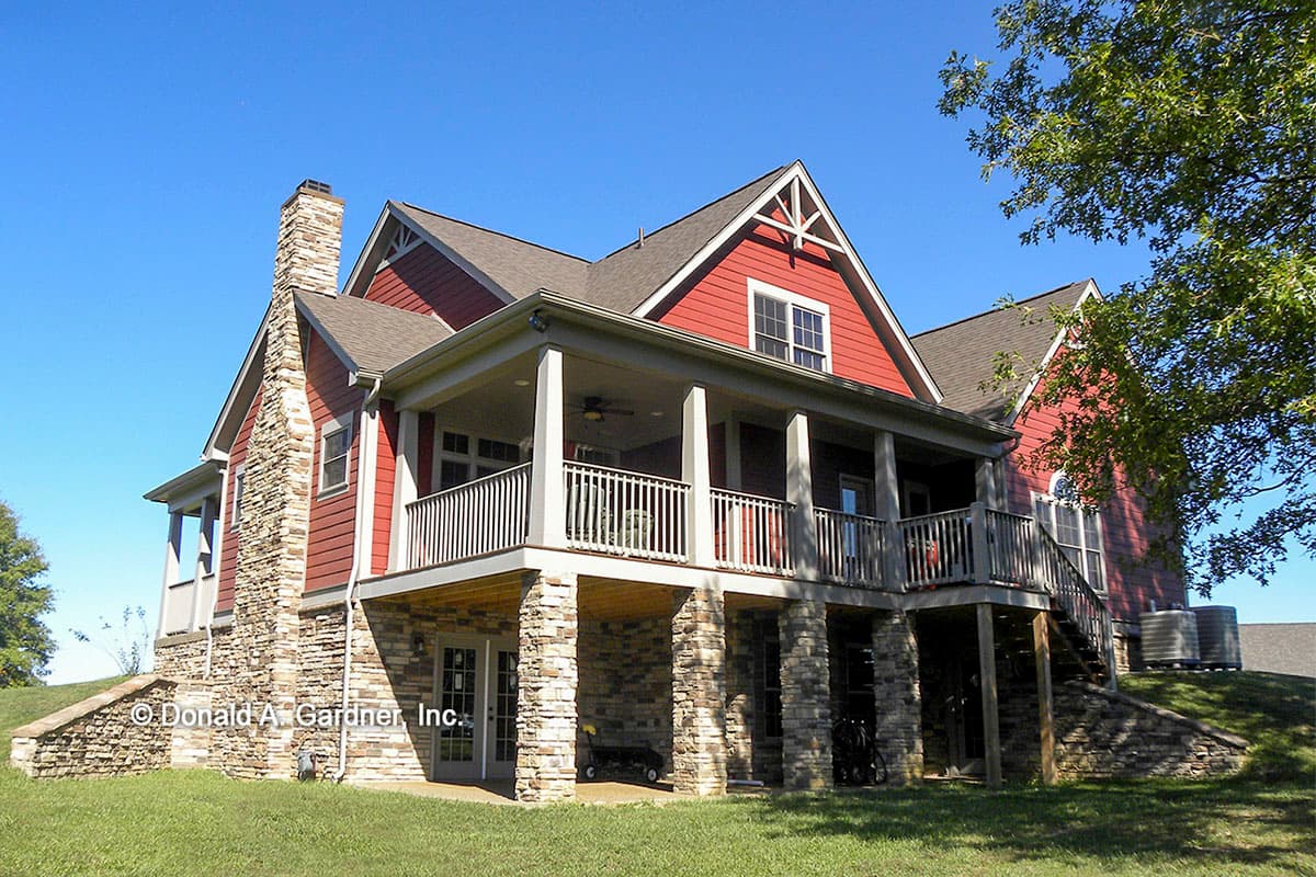 House plan exterior of a two-story home with stone foundation, wraparound porch, and prominent stone chimney.