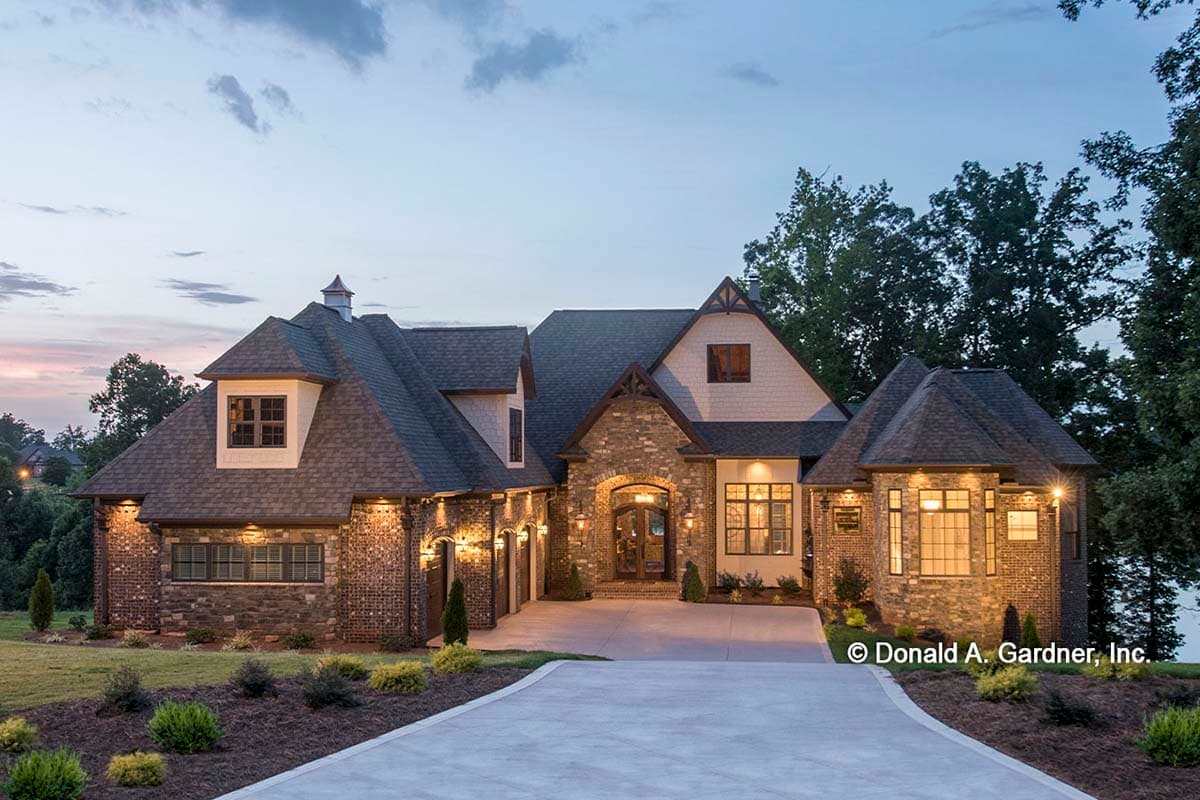 House plan exterior featuring brick and stone facade, multiple gables, arched entry, and dormers. Two-story structure with attached garage.