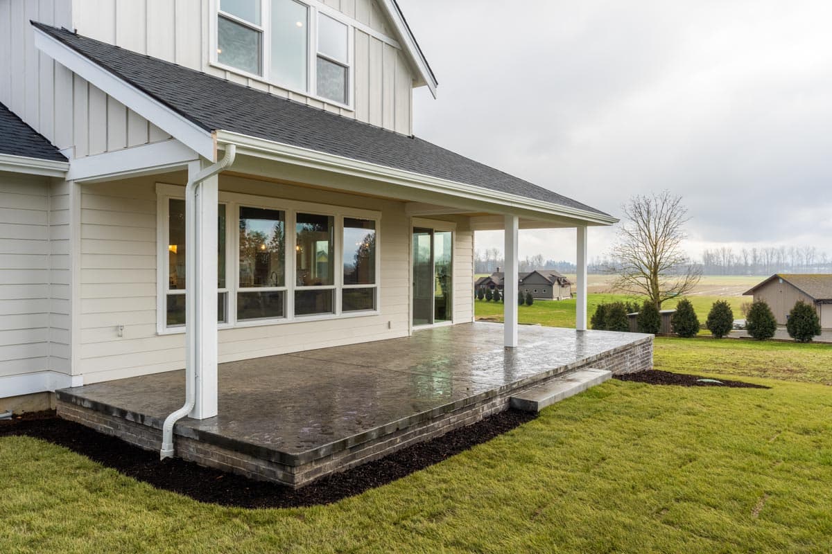 House plan exterior: Modern farmhouse style, two stories, covered patio with white columns, board and batten siding.