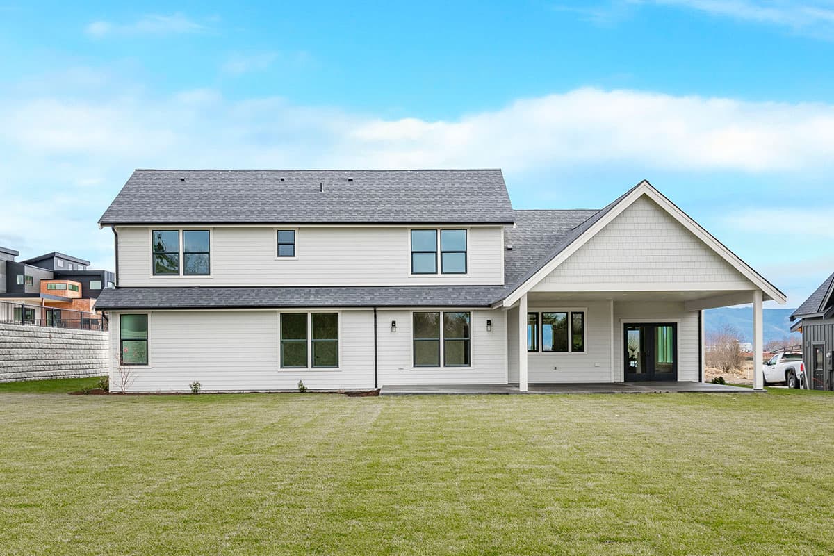 Two-story Modern Farmhouse exterior with white horizontal siding, large windows, and covered porch with gabled roof.