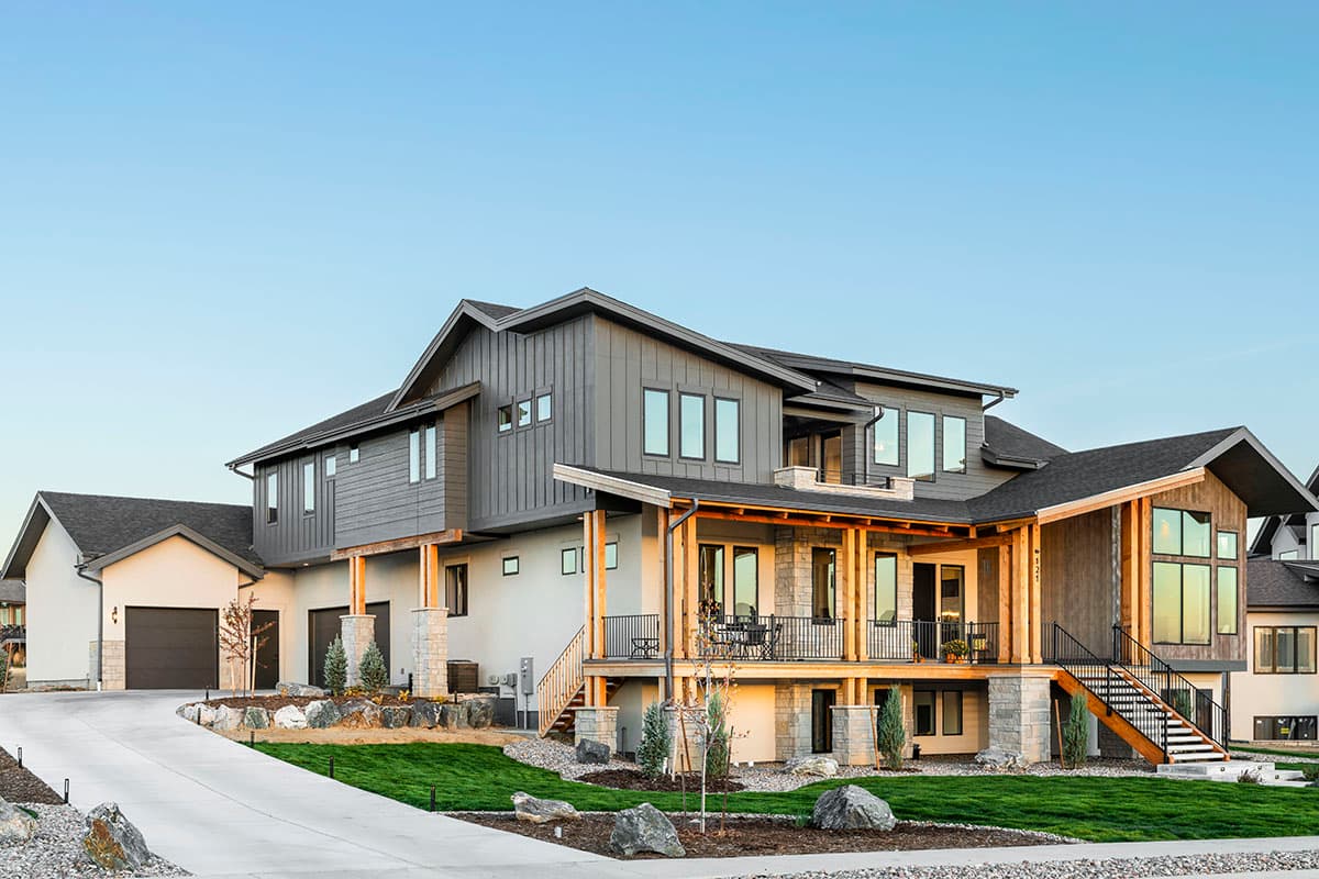 Modern house plan exterior with multiple gables, a covered deck, large windows, and a three-car garage.