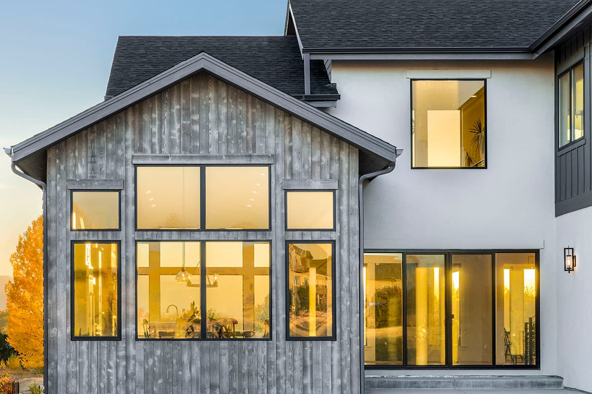 House plan exterior featuring vertical wood siding, gabled roof, and large grid windows on a modern home.