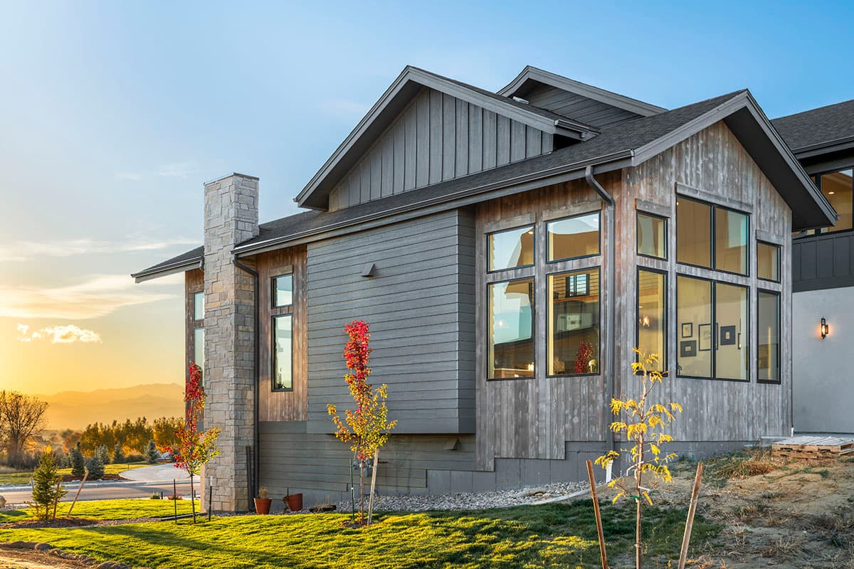Modern house plan exterior with stone chimney, vertical siding, wood siding, and large multi-pane windows.
