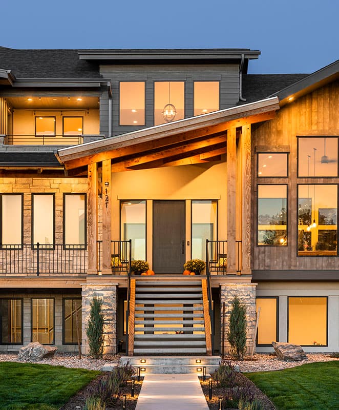 House plan exterior with a covered entry, stone and wood siding, multiple gables, and extensive windows.