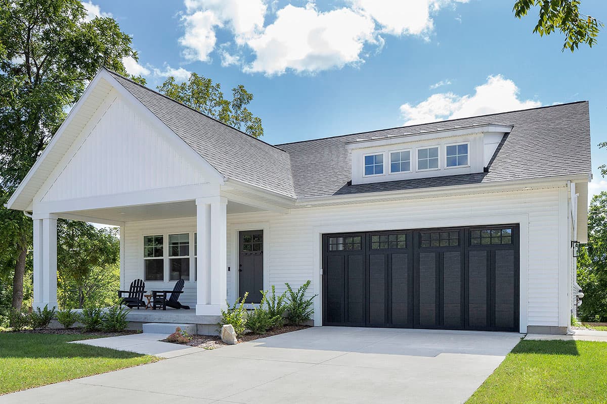 House plan exterior. One-story Modern Farmhouse with a gabled porch, dormer windows above the garage, and a dark garage door.