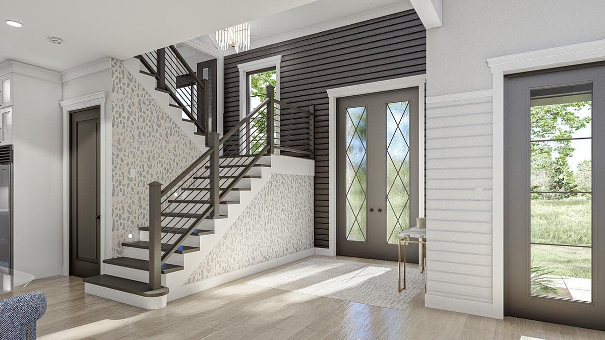 Interior view of house foyer showing staircase with dark railings, patterned wallpaper, and dual entry doors.