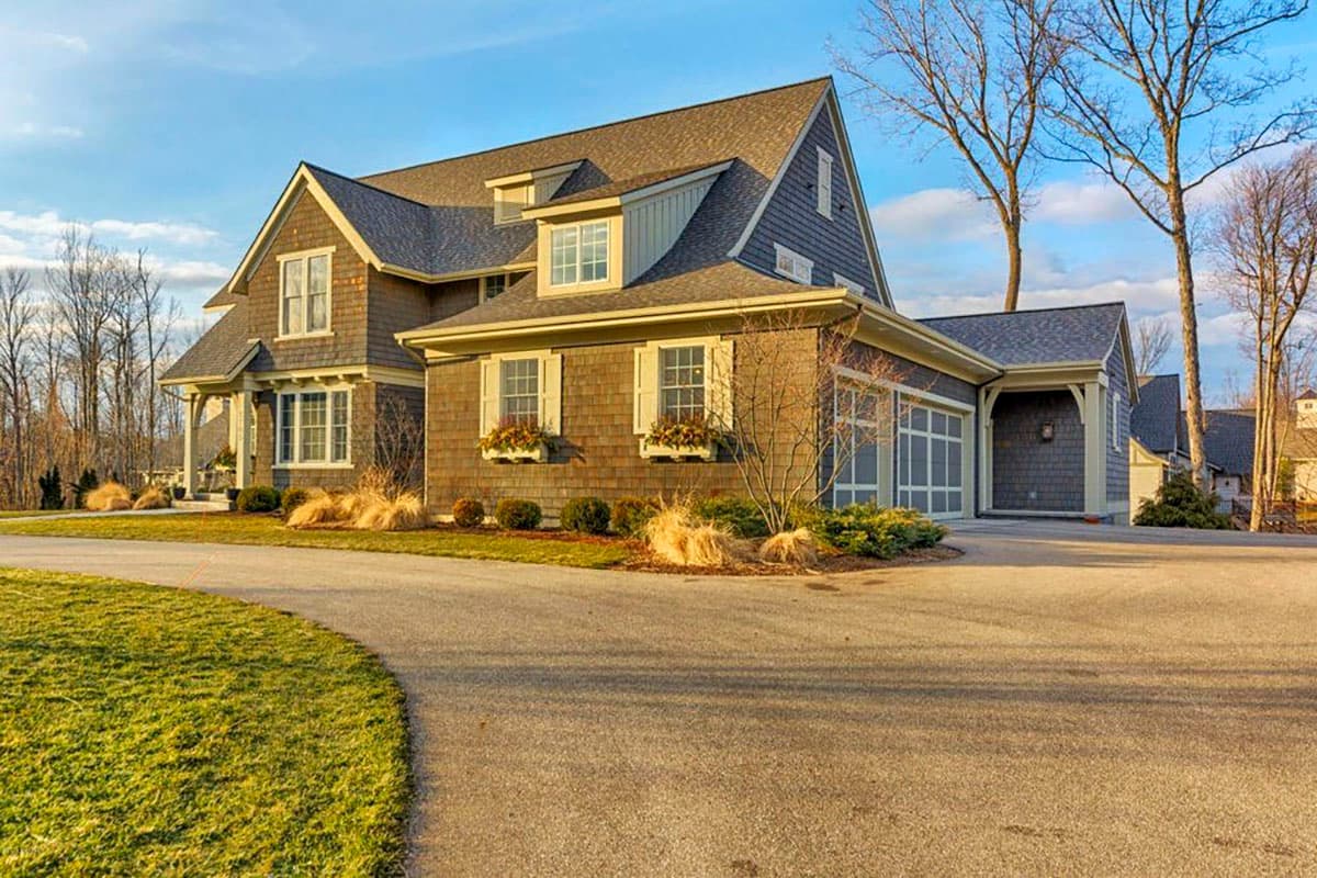 House plan exterior: Two-story home with gambrel rooflines, dormers, shingle siding, and attached garage.
