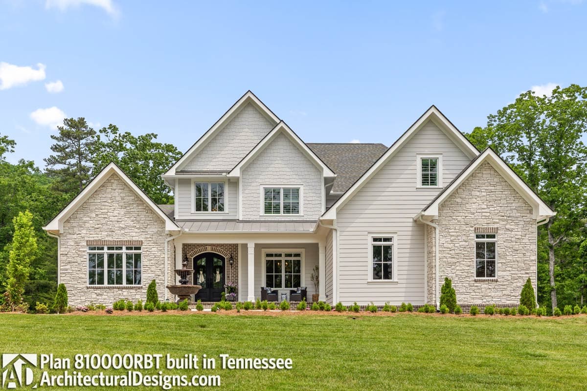 House plan exterior featuring stone accents, a covered porch with brick detail, multiple gables, and a metal roof.