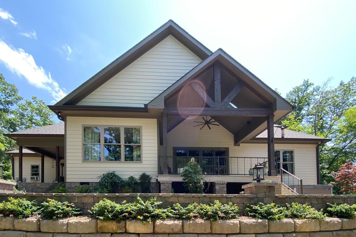 House plan exterior showing a two-story home with gables, exposed timber accents, and a covered rear deck.