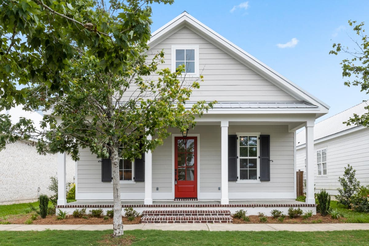 House plan exterior. One-story Craftsman home with a front porch, gabled roof, and decorative shutters on either side of the entrance.