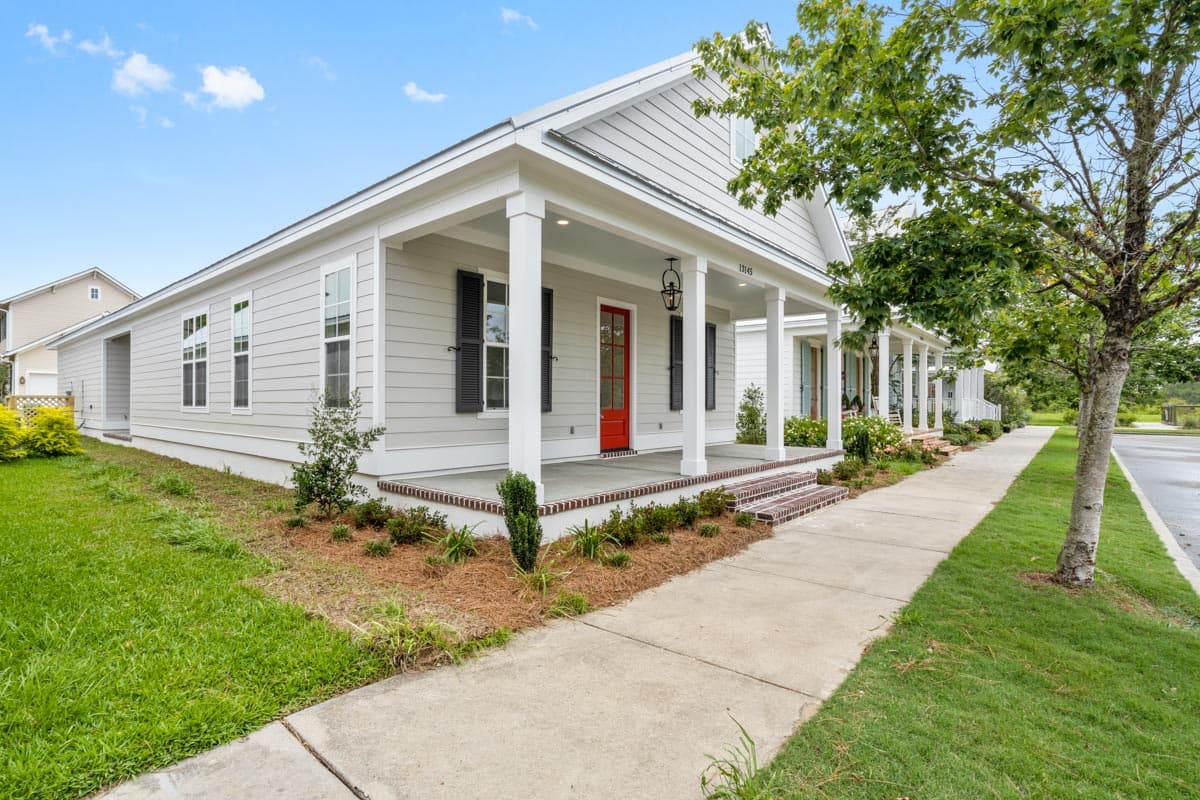 Craftsman style house plan exterior with a wide covered porch, central gable, and white siding.