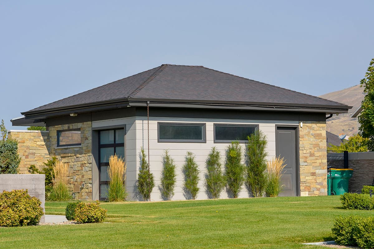 House plan exterior: Low-profile modern design with stone and siding, garage, and multiple long, horizontal windows.