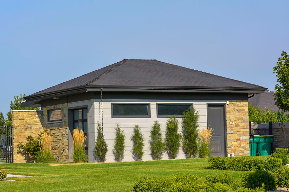 House plan exterior with stone accents, horizontal siding, a gabled roof, and dark gray door.
