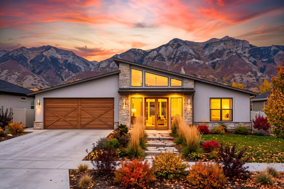 Modern ranch house plan exterior with a sloped roofline, stone accents, large wood garage doors, and triangular clerestory windows.