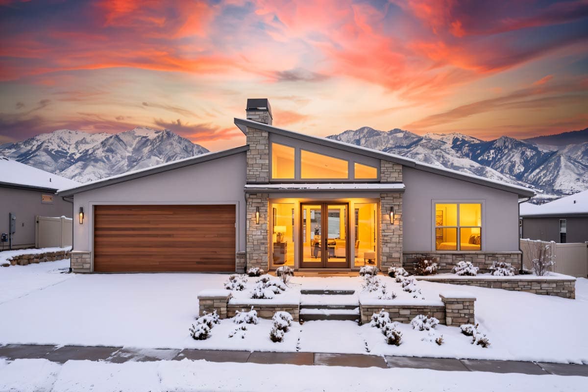 Modern house plan exterior with stucco, stone accents, wood garage door, angled roofline, and large windows.