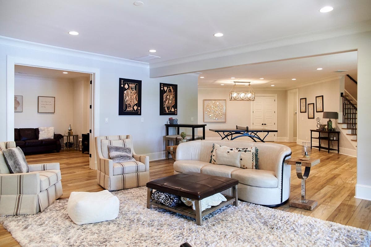 Interior view of a finished basement living area with seating, a ping pong table, and a staircase.