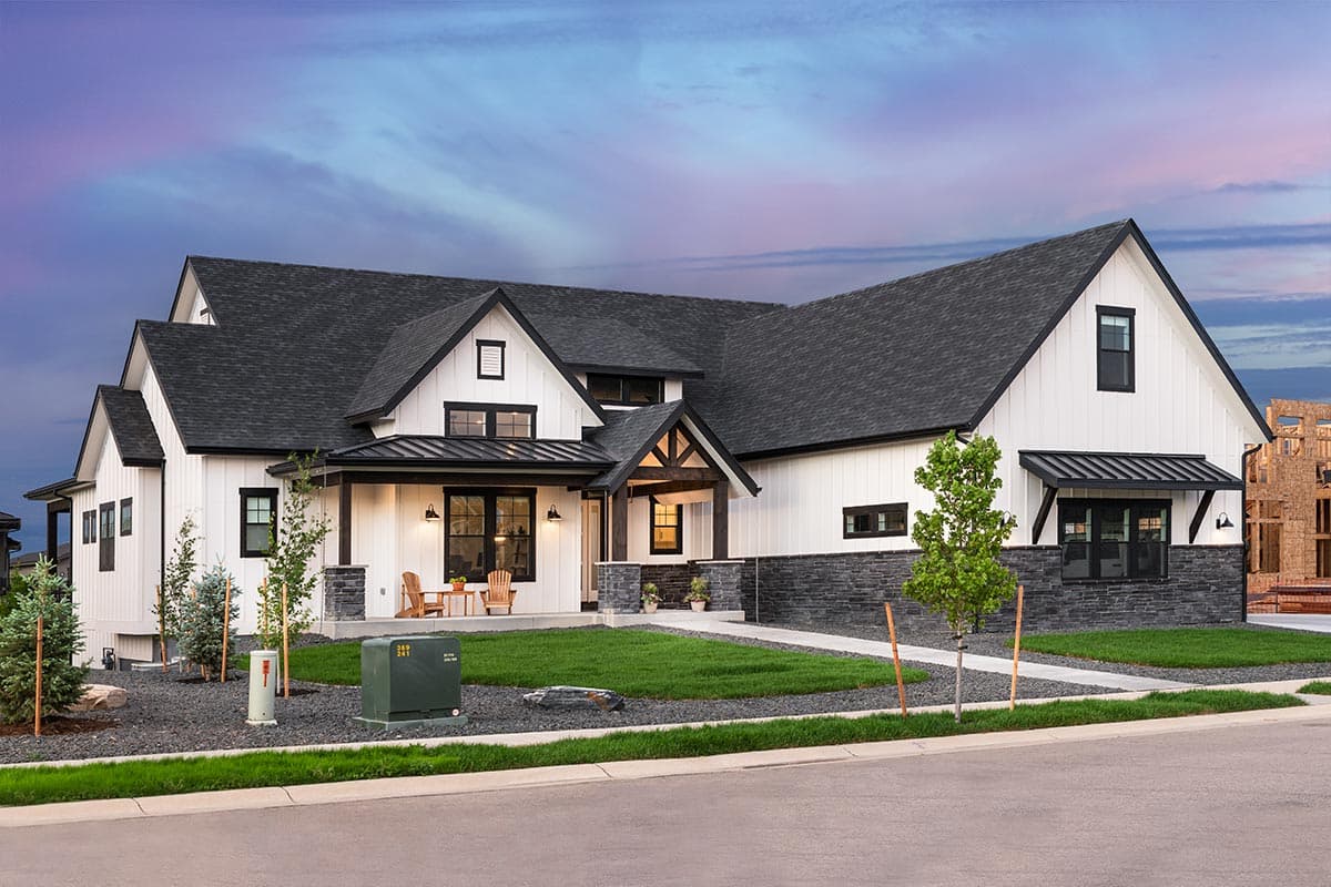 House plan exterior. Modern Farmhouse style with two stories, gabled rooflines, a covered porch, and a stone facade on the lower portion.