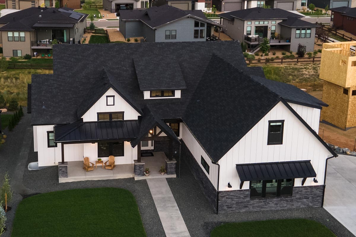 Modern Farmhouse house plan exterior with a covered porch, gables, dormers, and stone and board-and-batten siding.