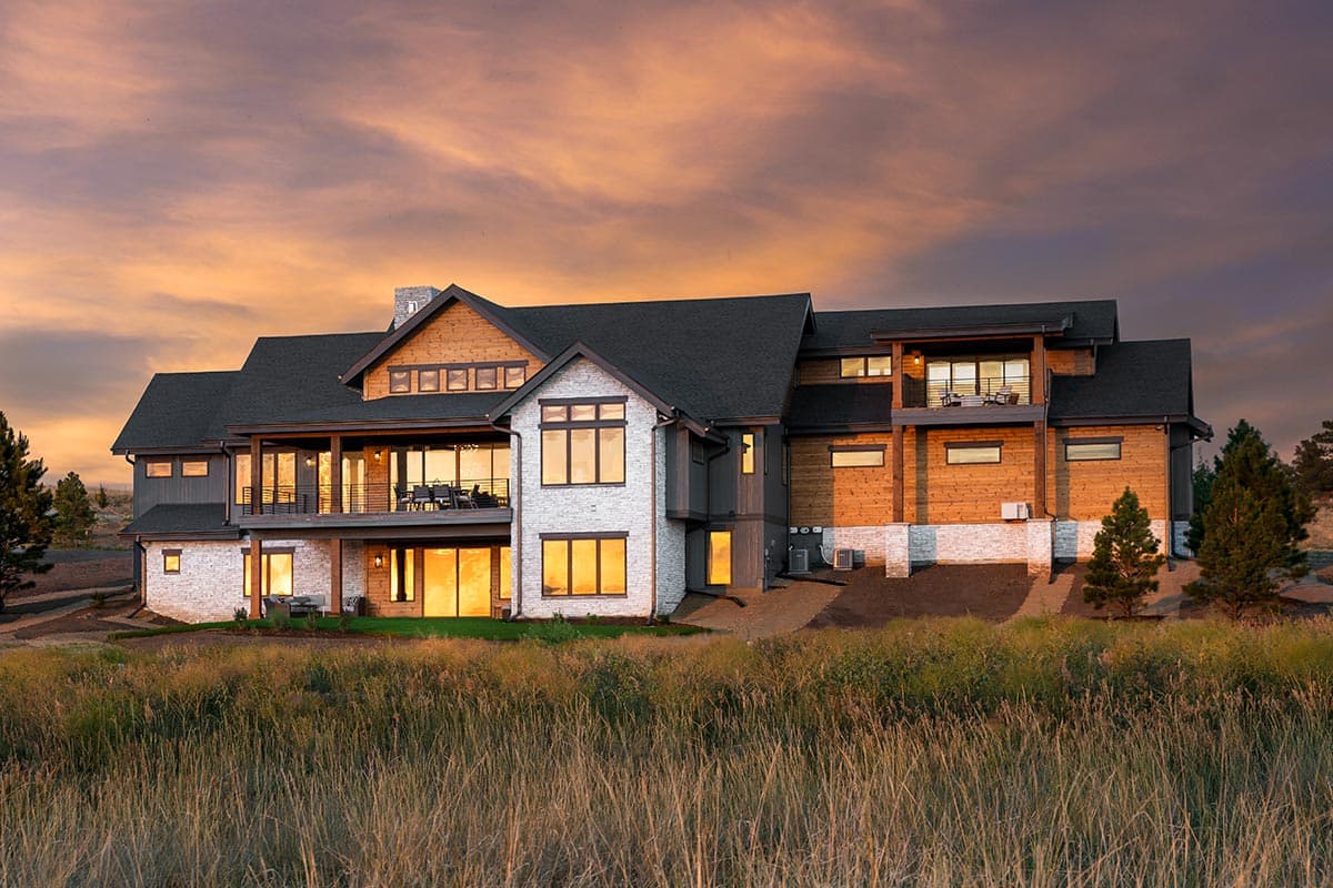 Modern house plan exterior with multiple levels, stone and wood siding, large windows, and balconies.
