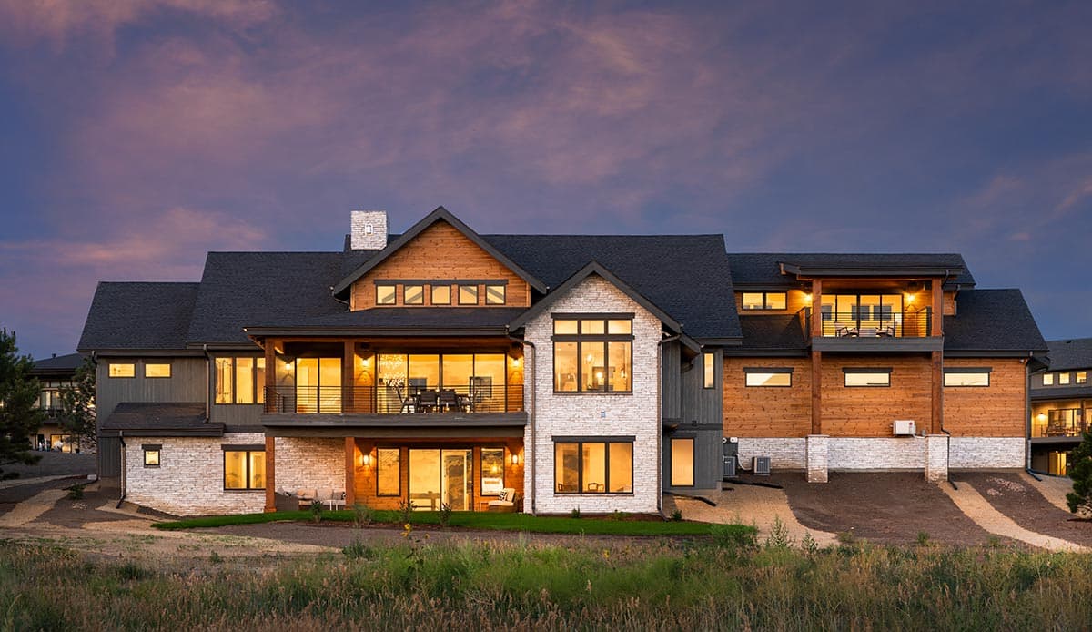 Modern house plan exterior with stone and wood facade, multiple levels, covered balconies, and large windows.