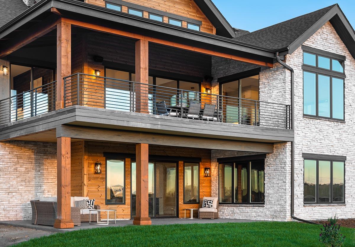 Modern house plan exterior with stone and wood siding, multi-level decks, and large windows.
