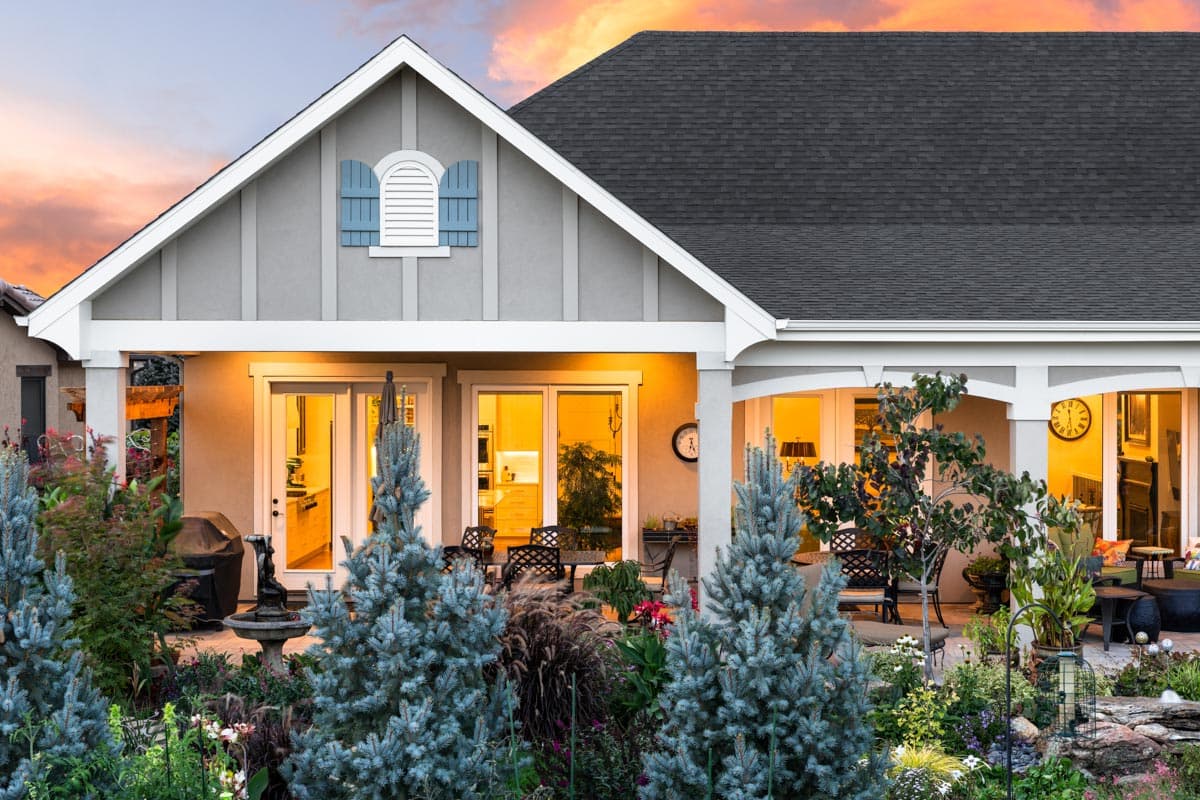 House plan exterior with gables, arched window with shutters, covered porch, and large sliding glass doors.