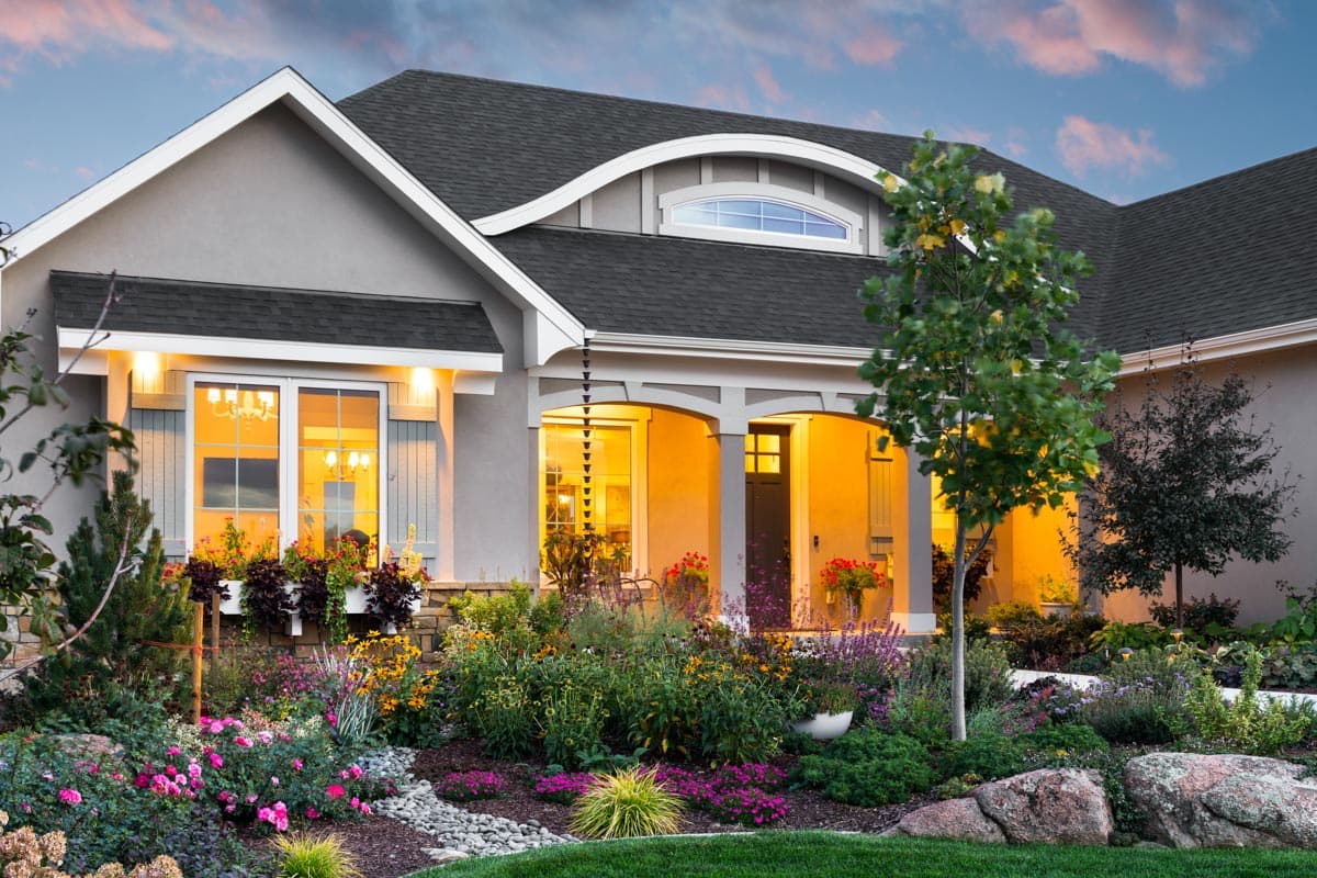 House plan exterior: Contemporary style with a covered entry porch, arched dormer, and multiple gables. Features large windows and stone accents.