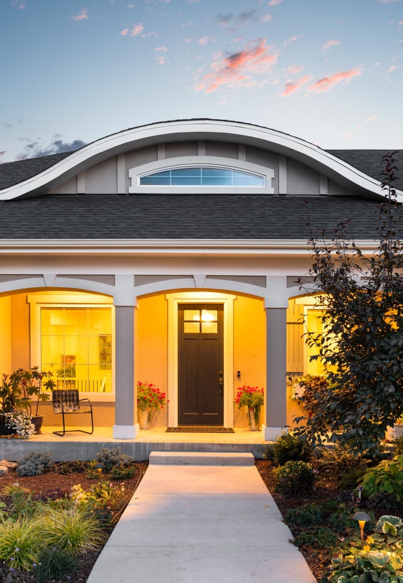 House plan exterior with arched roof dormer, covered porch, and glass-paneled front door.