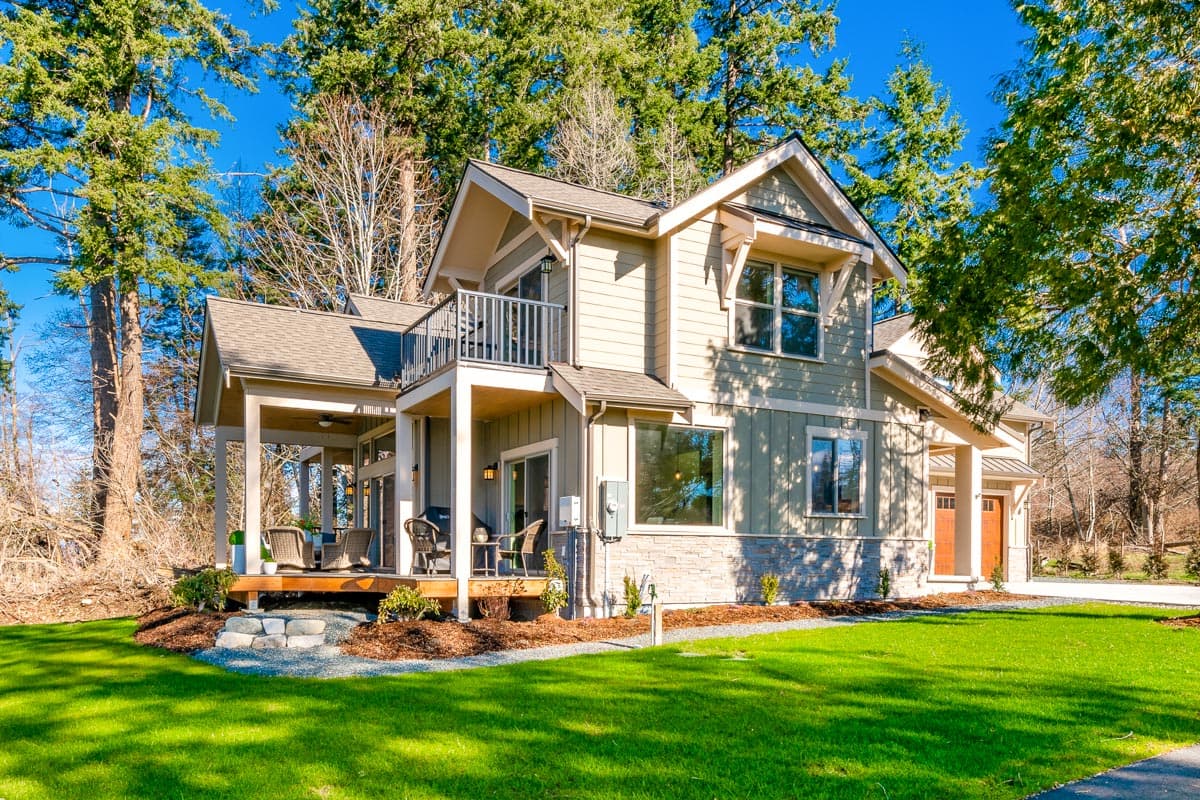 Two-story house plan exterior with a covered porch, second-story balcony, gables, and a two-car garage.