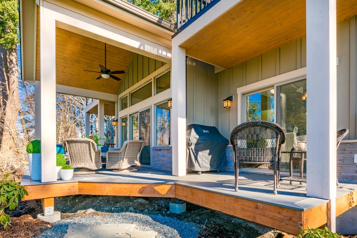 House plan exterior: Covered deck with wood ceiling, white columns, siding, and large windows.