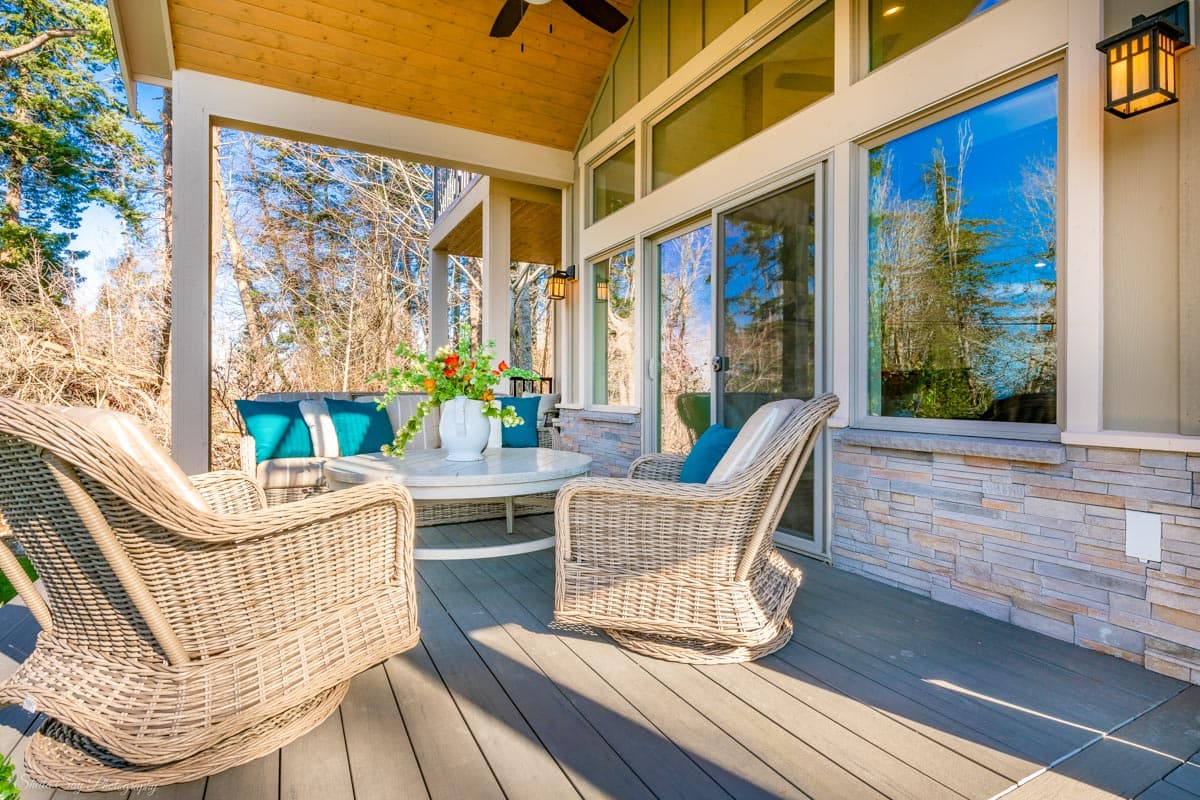 Covered porch with wood ceiling, stone veneer lower walls, sliding glass doors, and wicker seating.