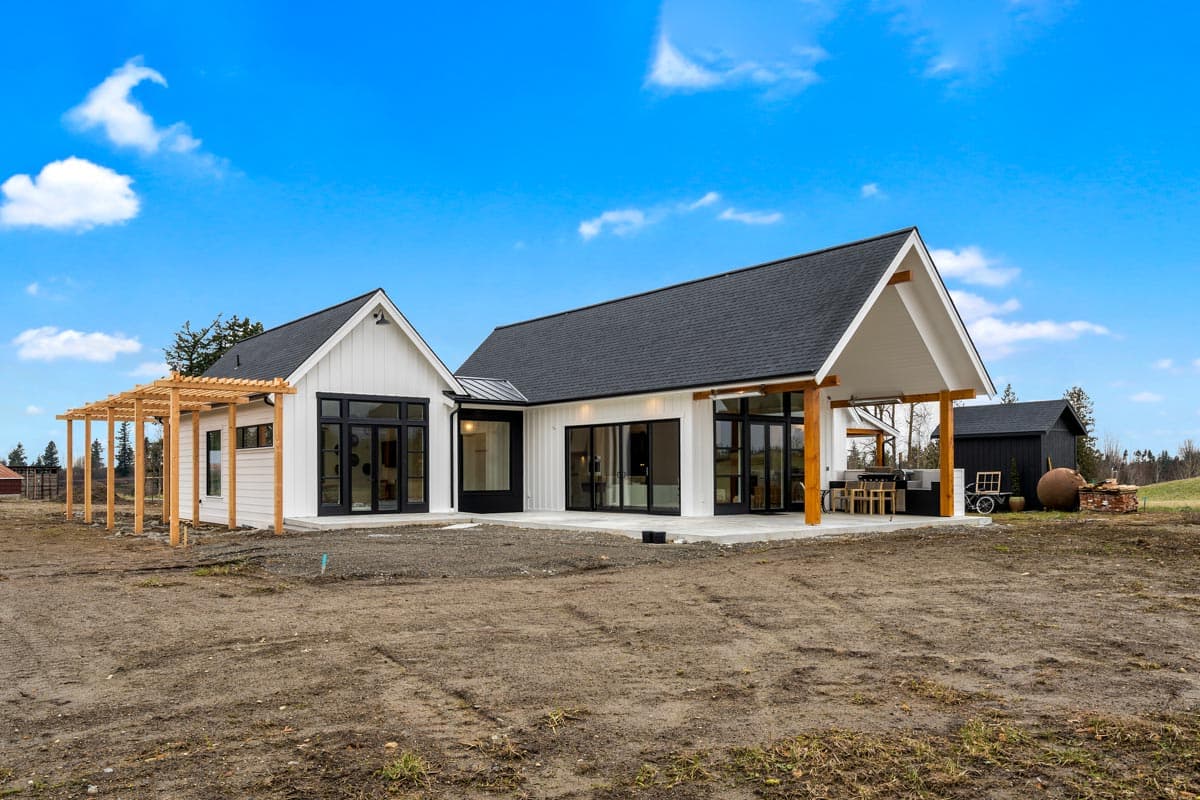 Modern Farmhouse exterior with white board-and-batten siding, large black-framed windows, covered patio, and wood pergola.