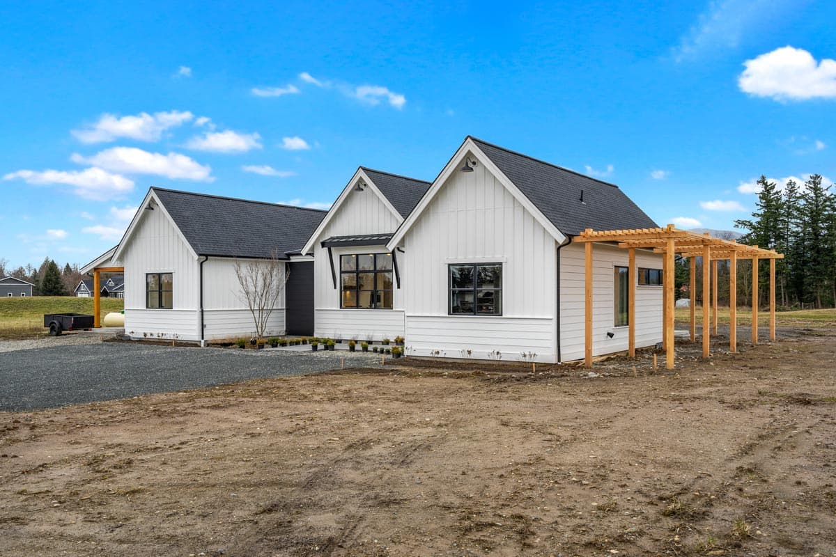 House plan exterior of a white Modern Farmhouse style home with gables, black-framed windows, and a wooden pergola.
