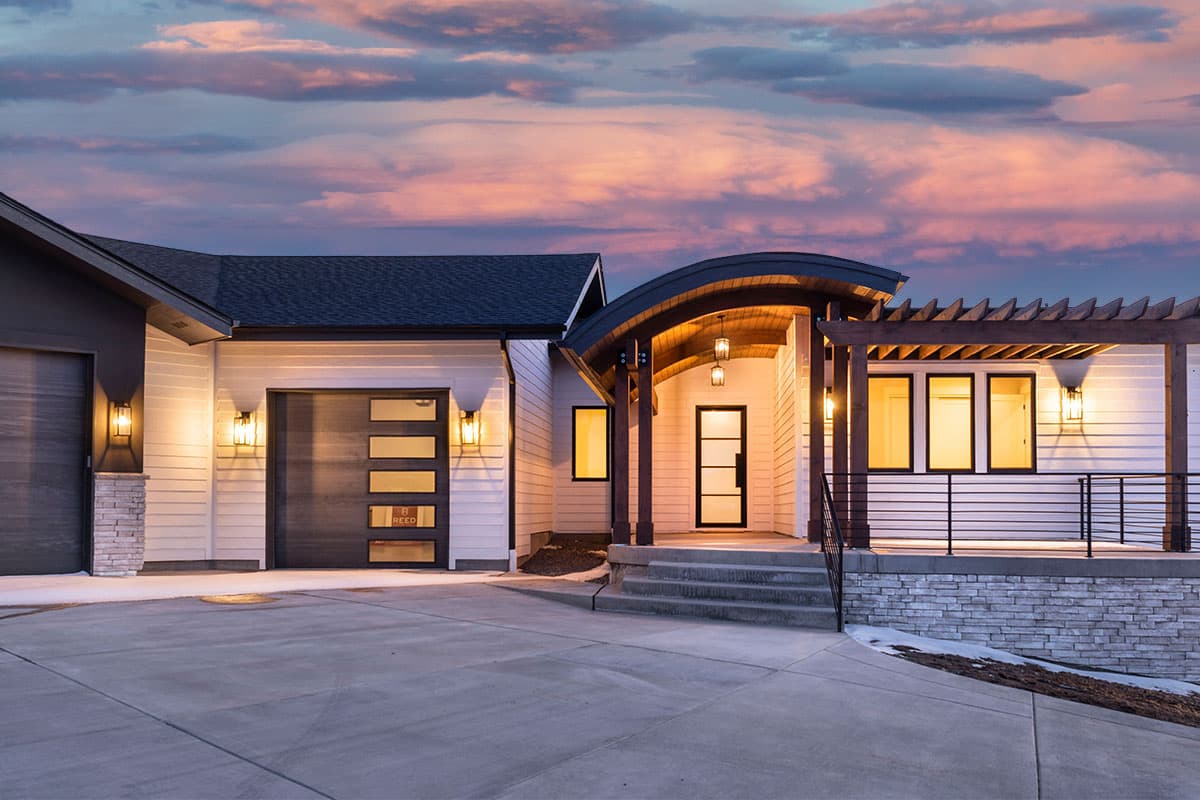 Modern house plan exterior with a curved entrance canopy, wood beams, two-car garage, and stone accents.