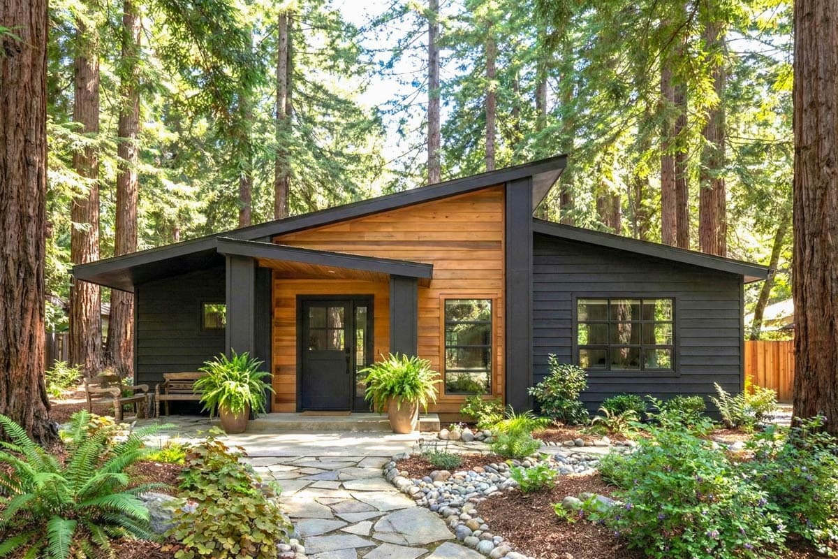 Modern house plan exterior with asymmetrical rooflines, wood and dark siding, covered entry, and large windows.