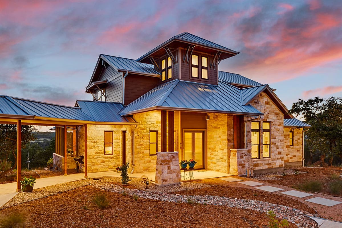House plan exterior with stone veneer, metal roof, and covered walkway. Features include a two-story structure and multiple gables.