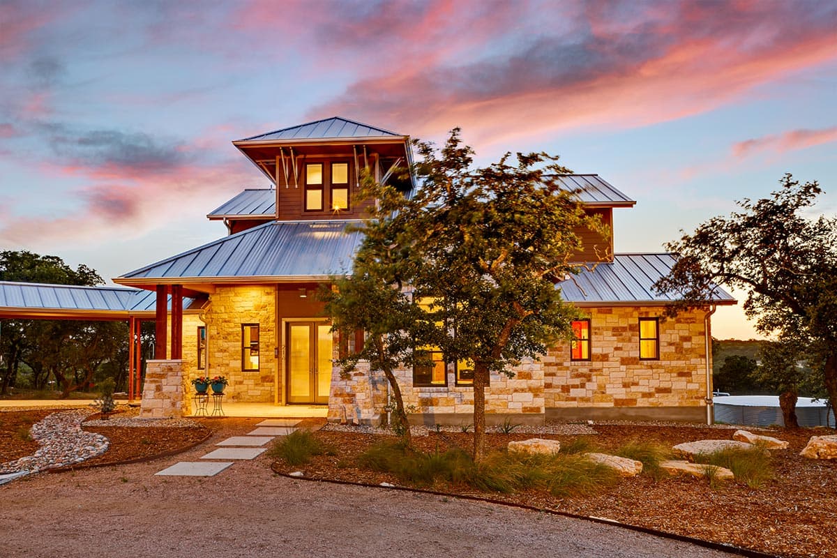 House plan exterior with stone facade, metal roof, multi-level rooflines, and covered walkway.