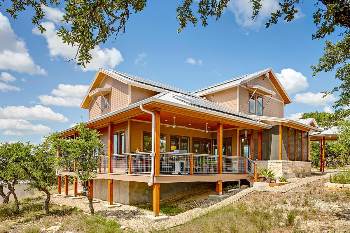 House plan exterior: Two-story Modern Farmhouse with wraparound porch, solar panels, and gabled dormers.