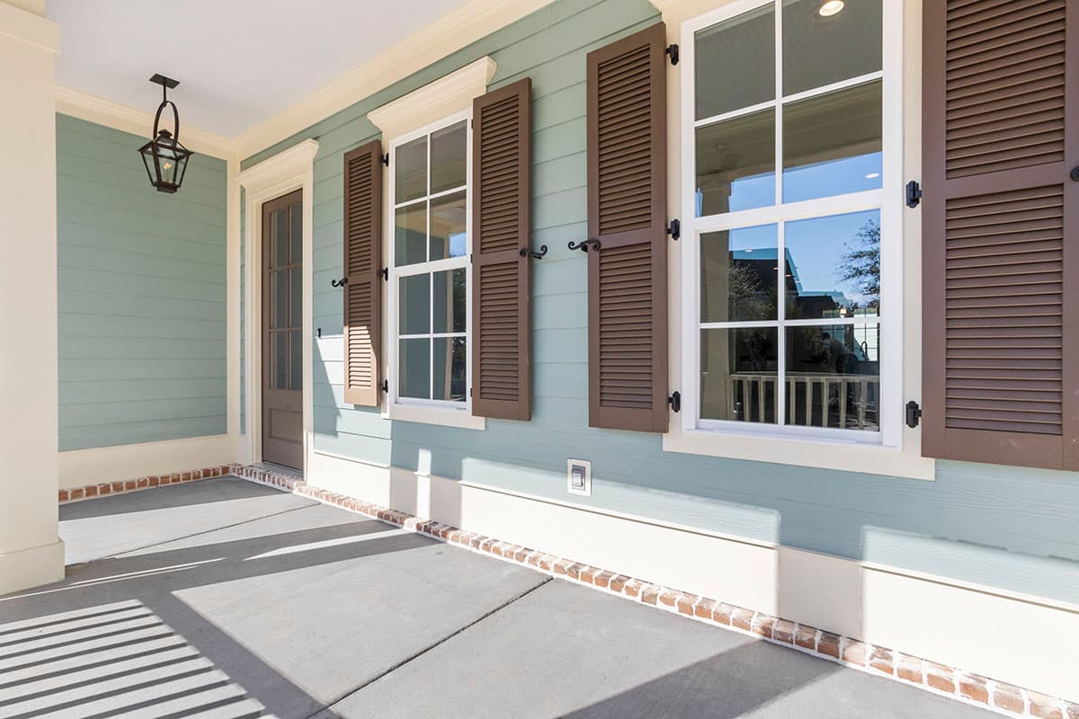 Exterior house plan featuring a covered porch with a lantern, clapboard siding, shutters, and multi-pane windows.