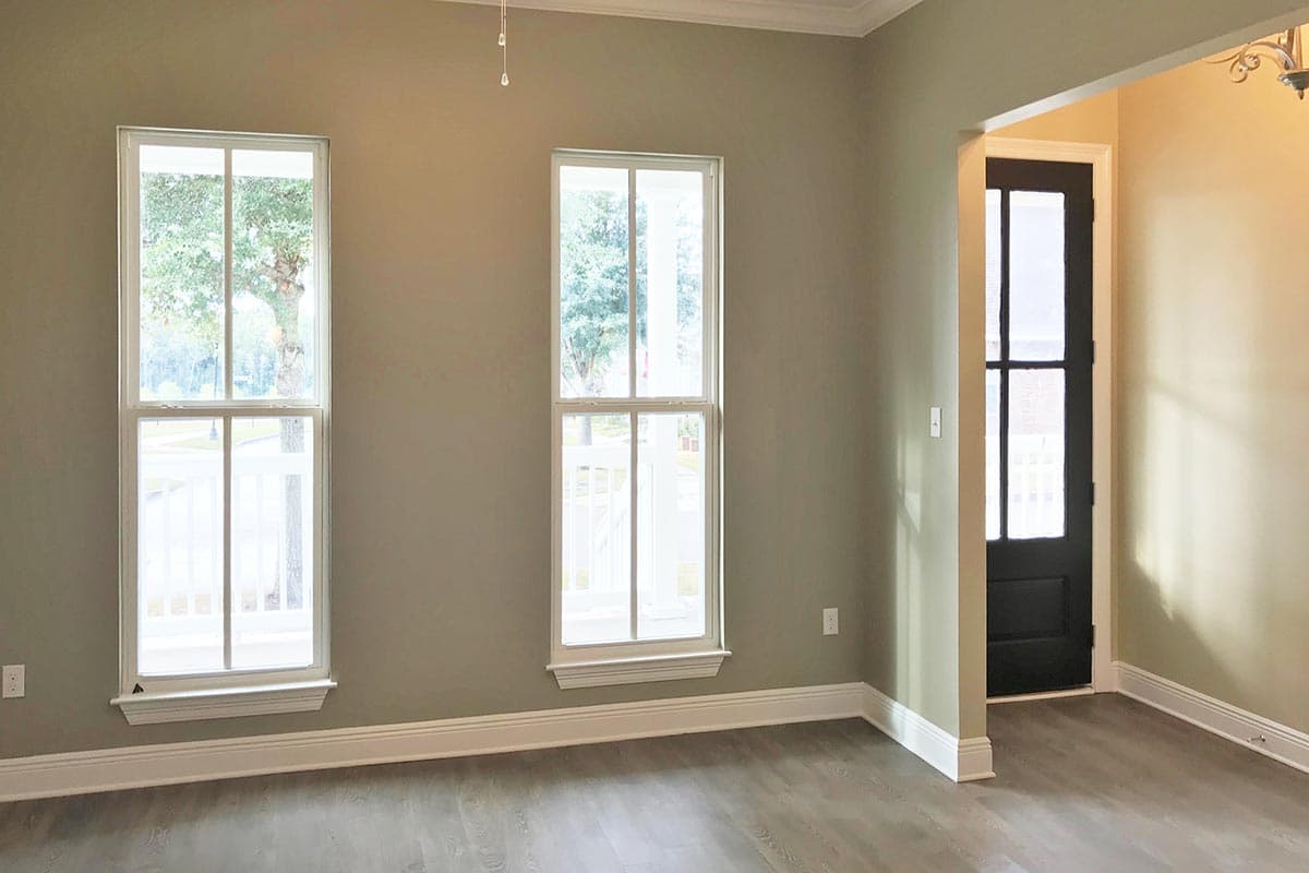 Interior view of a room with two double-hung windows and a dark paneled door leading outside.