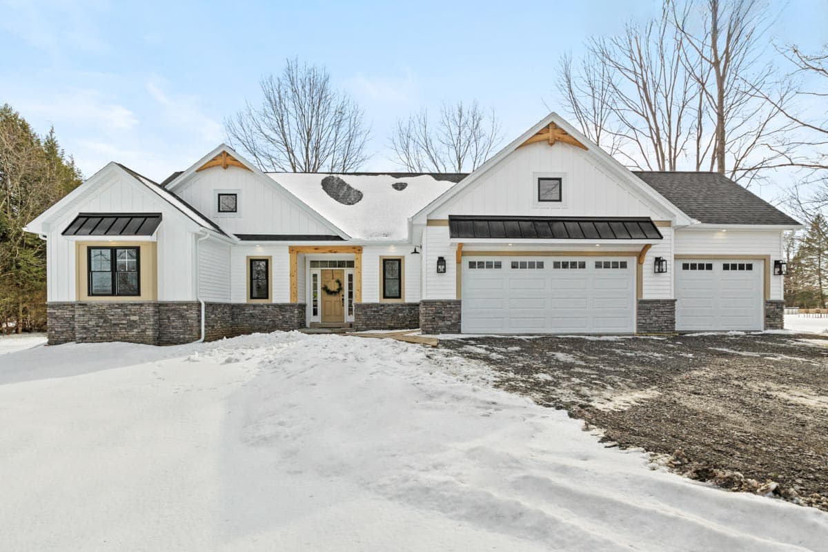 House plan exterior: Modern Farmhouse style, one-story with gabled roof, stone base, and a three-car garage.