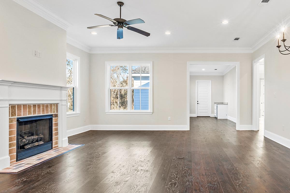 Living room interior with fireplace, large window, ceiling fan, and doorways to other rooms.