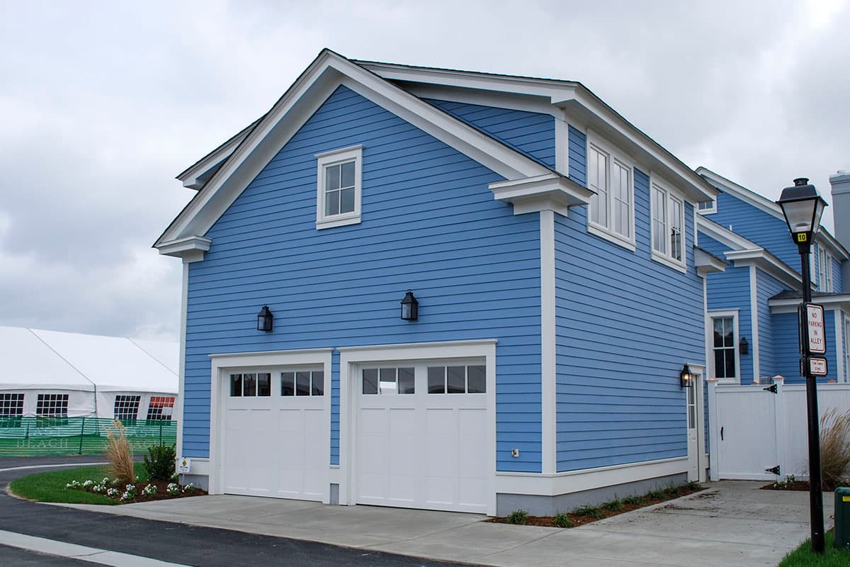 House plan exterior with two stories. Features include a gabled roof, white trim, and a two-car garage. Blue siding is visible.